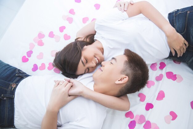 Glückliche asiatische Paare auf dem Bett zu Hause