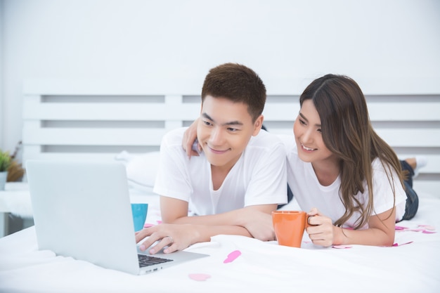 Glückliche asiatische Paare auf dem Bett zu Hause