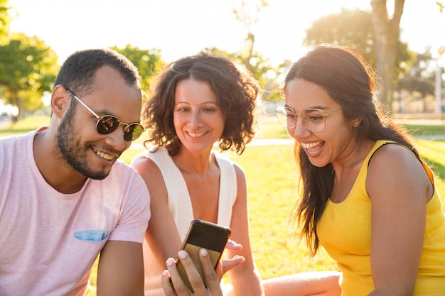 Glückliche aufgeregte Gruppe Freunde, die Video am Telefon aufpassen