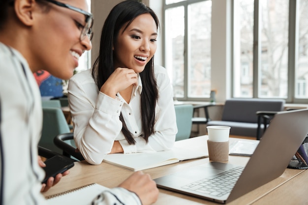 Glückliche aufgeregte junge Geschäftsfrauen, die Laptop-Computer verwenden.