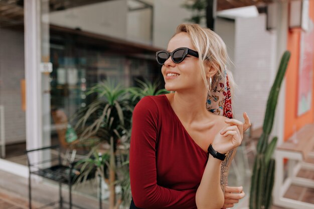 Glückliche blonde Frau in der Sonnenbrille und im roten Kleid