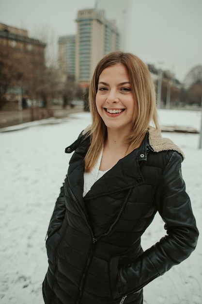 Glückliche blonde frau in einer daunenjacke im freien