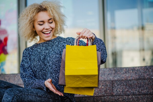 Glückliche blonde Frau mit Papiertüten