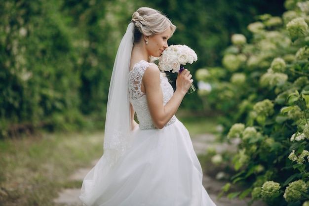 Glückliche Braut ihren Strauß weißer Rosen riechend