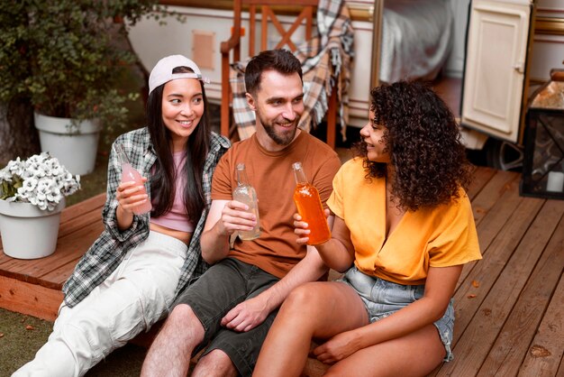 Glückliche drei Freunde, die draußen trinken