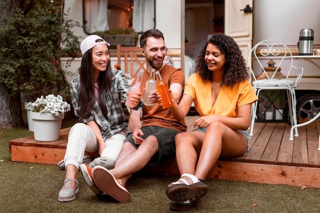 Glückliche drei Freunde sitzen und Getränke teilen