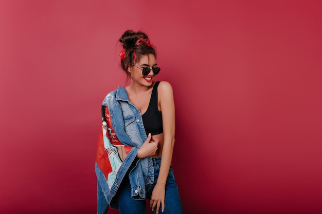 Glückliche dunkelhaarige Frau trägt Jeanskleidung, die Zeit auf Fotoshooting verbringt