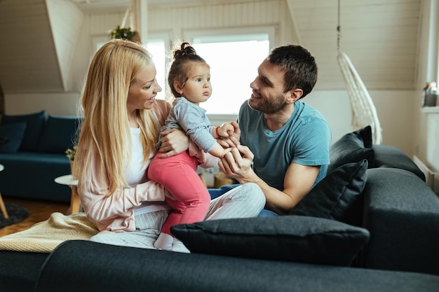 Glückliche Eltern, die sich zu Hause mit ihrer kleinen Tochter amüsieren