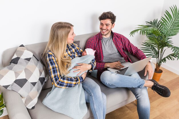 Glückliche Eltern mit schlafendem Baby, das Laptop verwendet