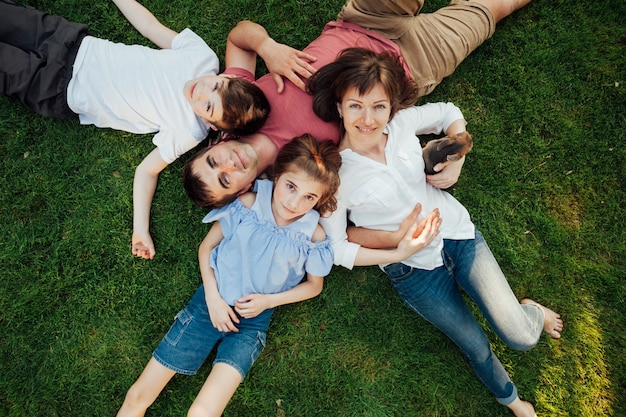 Glückliche Eltern und Kinder, die auf Gras am Park liegen