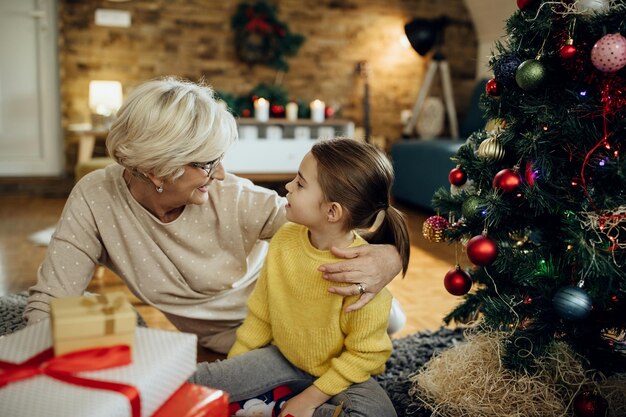 Glückliche Enkelin und Großmutter unterhalten sich, während sie Weihnachten zu Hause genießen