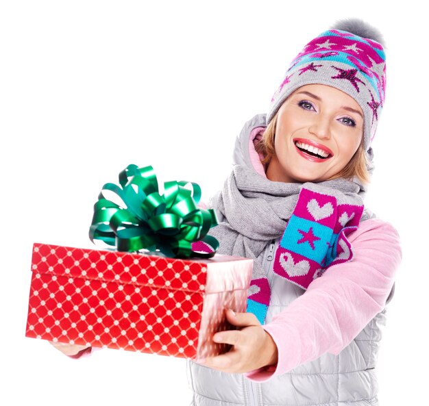 glückliche erwachsene Frau, die ein Weihnachtsgeschenk in einer Winteroberbekleidung lokalisiert auf Weiß gibt