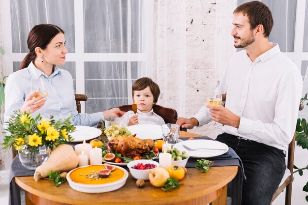 Glückliche Familie, die am festlichen Tisch trinkt