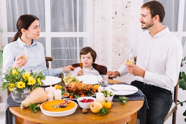 Glückliche Familie, die am festlichen Tisch trinkt