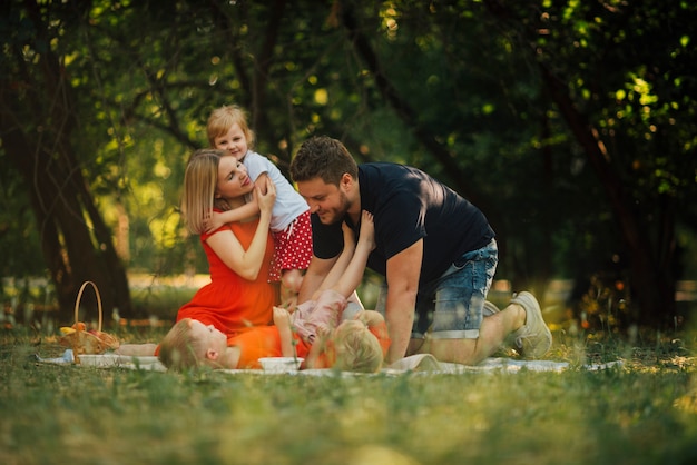 Glückliche Familie, die auf einer Picknickdecke spielt