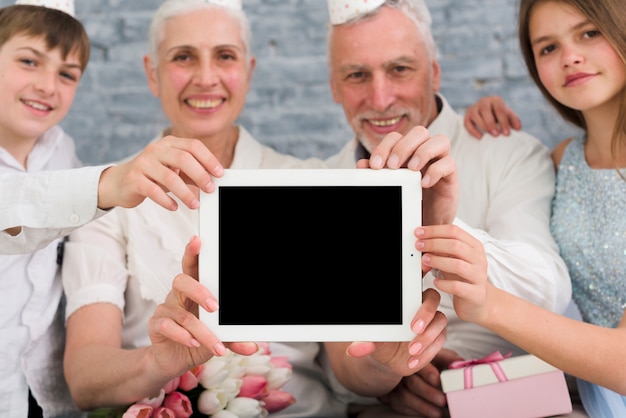 Glückliche Familie, die digitale Tablette des leeren Bildschirms zeigt