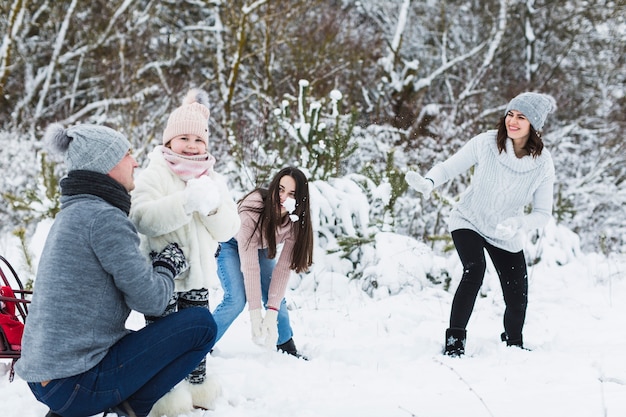 Glückliche Familie, die Schneebälle spielt