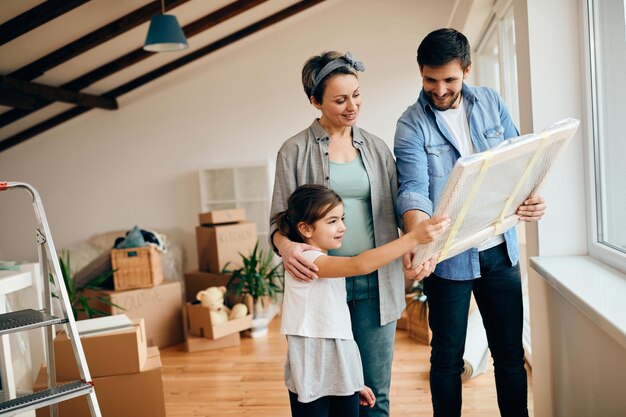 Glückliche Familie, die sich eingewickeltes Gemälde ansieht, während sie in ein neues Zuhause umzieht