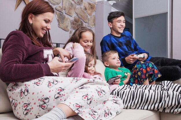 Glückliche Familie, die Technologien auf Sofa verwendet