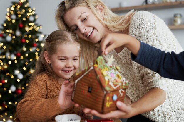 Glückliche Familie, die verziertes Lebkuchenhaus betrachtet