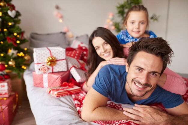 Glückliche Familie, die Weihnachten im Bett feiert