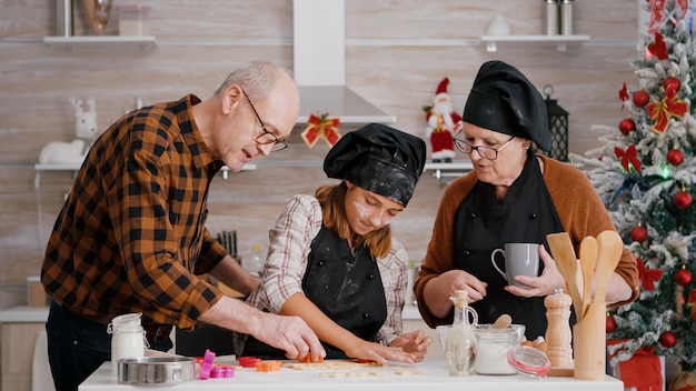 Glückliche Familie, die Weihnachtsköstliches Lebkuchendessert mit Keksform zubereitet