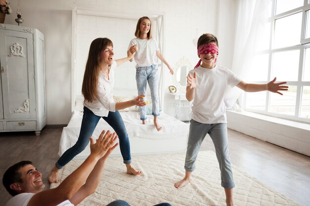 Glückliche Familie, die zu Hause den Buff des blinden Mannes spielt