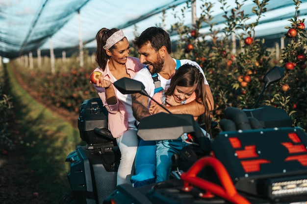 Glückliche familie, die zusammen genießt, während sie äpfel im obstgarten auswählt.