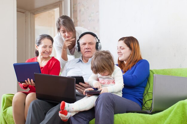 Glückliche Familie genießt mit wenigen verschiedenen Laptops