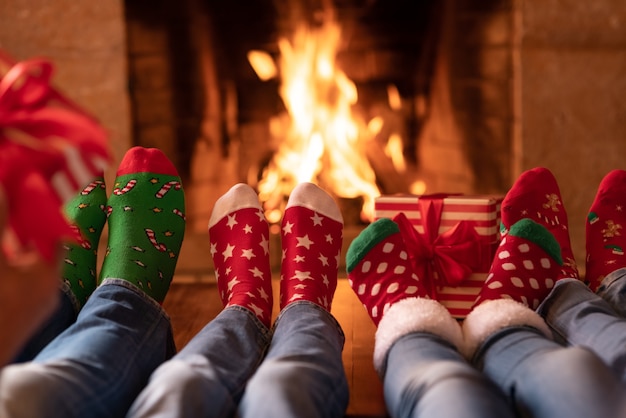 Glückliche familie in weihnachtssocken am kamin muttervater und kinder in der weihnachtszeit
