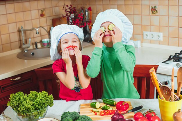 glückliche Familie lustige Kinder bereiten den frischen Gemüsesalat in der Küche vor