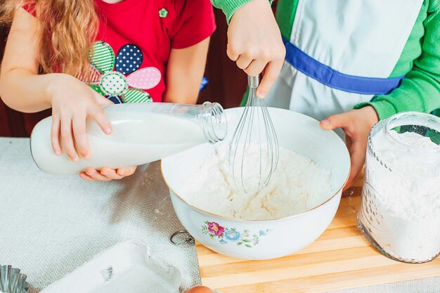 glückliche Familie lustige Kinder bereiten den Teig vor, backen Kekse in der Küche