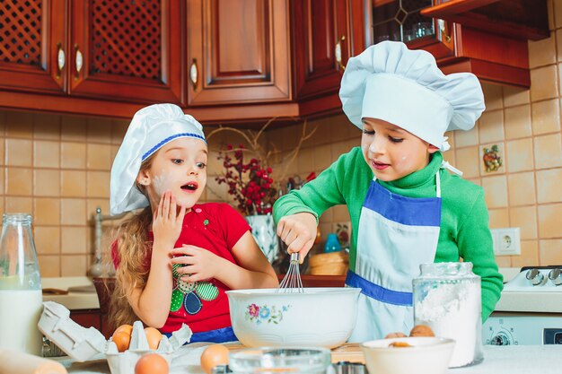 glückliche Familie lustige Kinder bereiten den Teig vor, backen Kekse in der Küche