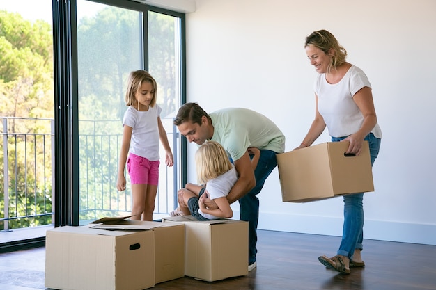 Glückliche Familie mit Kindern nahe Kartonschachteln, die im Wohnzimmer stehen