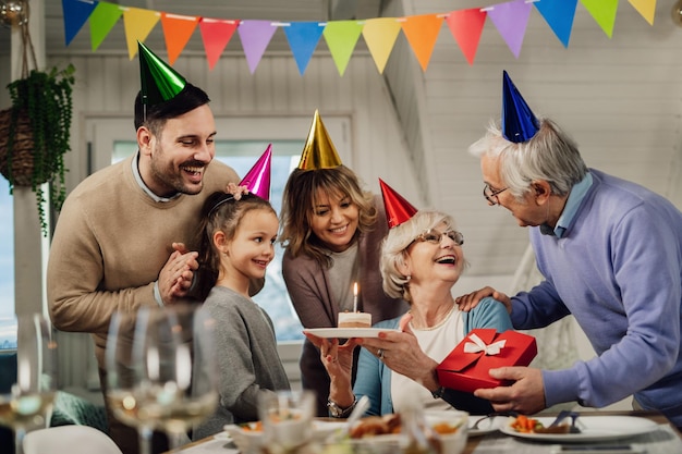 Glückliche Familie mit mehreren Generationen überrascht Seniorin mit einer Party an ihrem Geburtstag