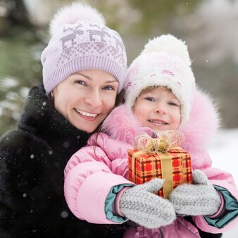 Glückliche familie mit weihnachtsgeschenkbox im winterpark