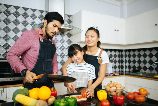 Glückliche Familienhilfe, die zusammen zu Hause Mahlzeit in der Küche kocht.