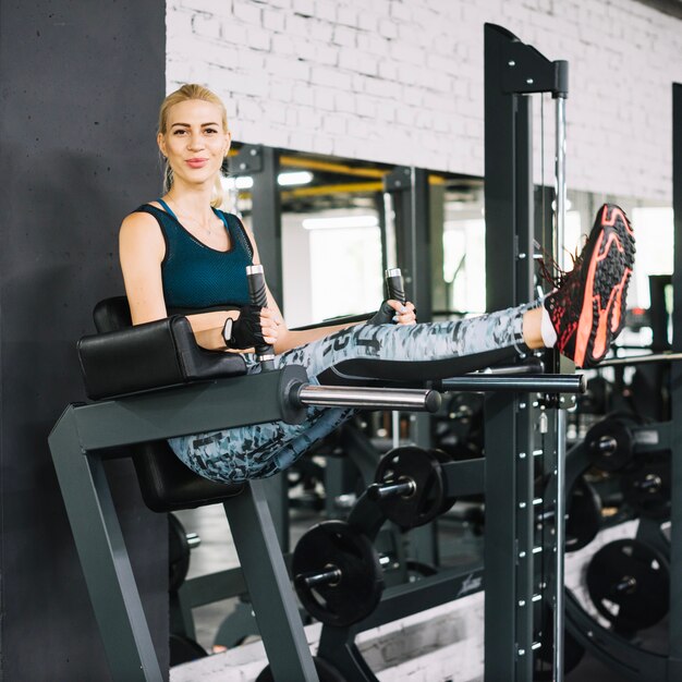 Glückliche Frau auf Simulator in der Turnhalle