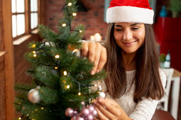 Glückliche Frau des mittleren Schusses, die den Weihnachtsbaum verziert