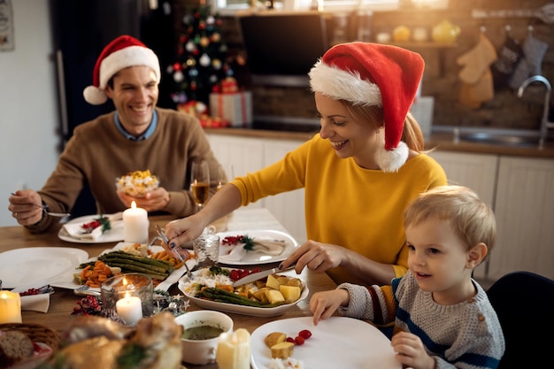 Glückliche Frau, die am Weihnachtstag im Familienessen am Esstisch genießt