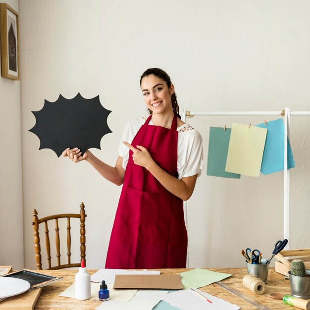 Glückliche Frau, die auf die Spracheblase gemacht vom Papier zeigt