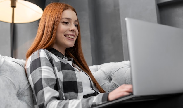 Glückliche Frau, die auf Laptop schaut