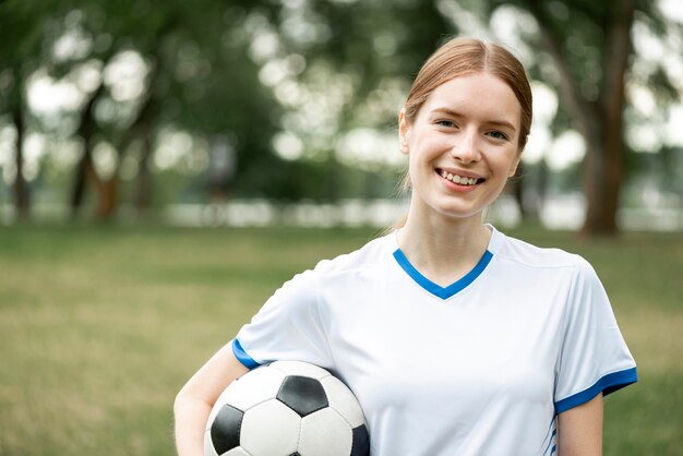 Glückliche Frau, die Ball draußen hält