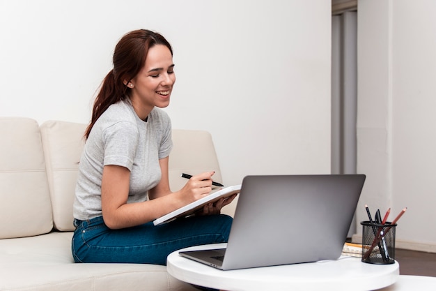 Glückliche Frau, die beim Betrachten des Laptops arbeitet