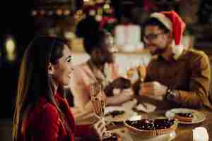 Kostenloses Foto glückliche frau, die champagner trinkt, während sie weihnachten mit ihren freunden zu hause feiert