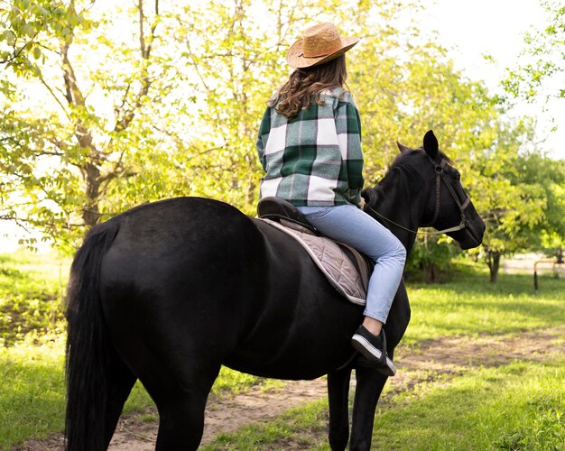 Glückliche Frau, die draußen auf einem Pferd reitet