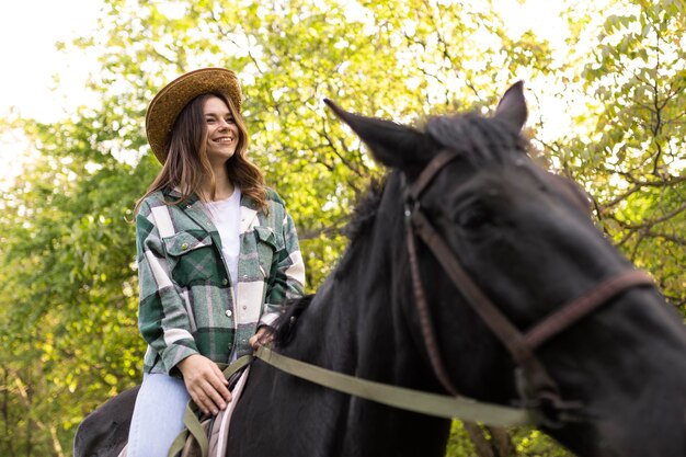 Glückliche Frau, die draußen auf Pferd reitet