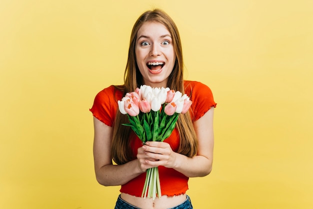 Kostenloses Foto glückliche frau, die einen blumenstrauß von tulpen hält