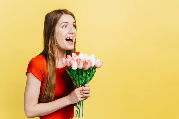 Glückliche Frau, die einen Blumenstrauß von Tulpen mit Kopienraum hält