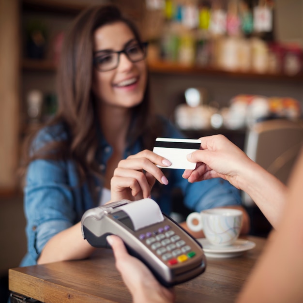 Glückliche Frau, die für Café mit Kreditkarte zahlt